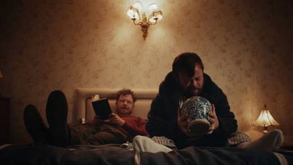 Quelle: Katholisches Filmwerk, Frankfurt zwei Männer in einem Zimmer, von denen der eine eine Urne in den Händen hält